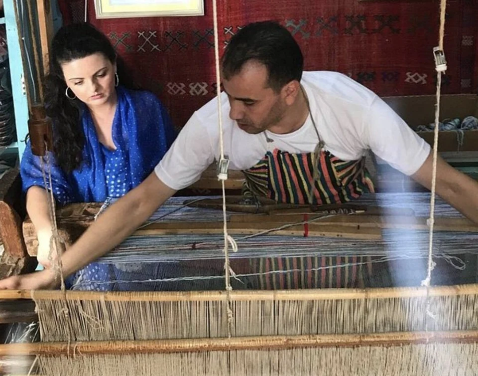 A guest and Rachid weaving side by side at a traditional Moroccan loom